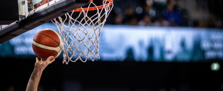 A basketball player tossing a basketball into a net