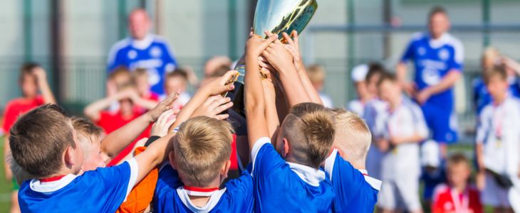 Kids raising a trophy into the air at a sports game