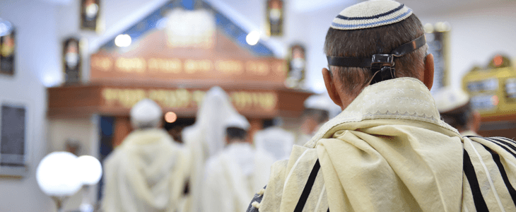 a man prays at a Jewish temple with others people