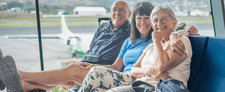 three people sit in an airport smiling