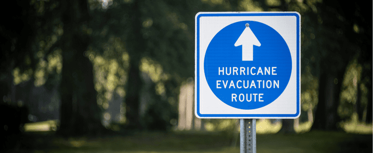 An emergency evacuation route road sign with a stormy sky in the background.