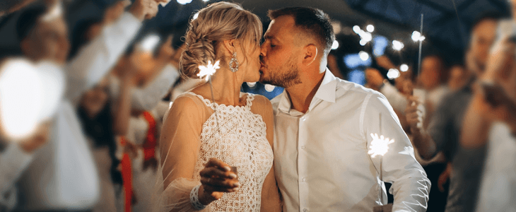 a bride and groom kiss under sparklers